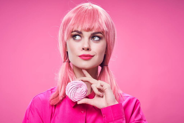 Bella donna in camicia rosa con un biscotto in mano e una parrucca  - Foto, immagini