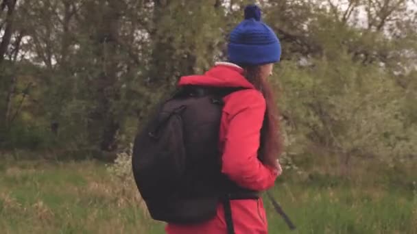 безкоштовна щаслива мандрівна жінка, що йде з рюкзаком на лісовій дорозі, махає рукою за мною і посміхається. концепція подорожей та пригод. свобода і здоровий спосіб життя. здорова дівчина подорожує
 - Кадри, відео
