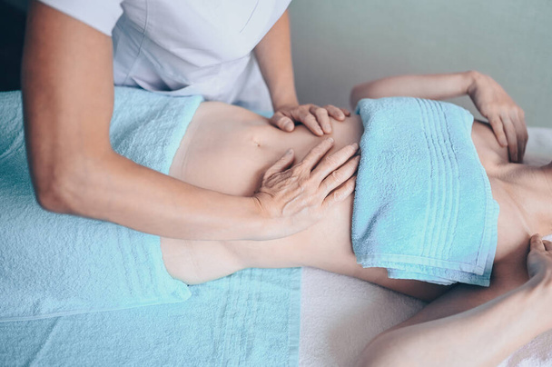 Junge unkenntliche Frau liegt auf Massagetisch und genießt therapeutische Massage. Körperpflege, Abnehmkonzept. Handmasseur Massagetherapeut tut Anti-Cellulite-Massage in Kurklinik - Foto, Bild