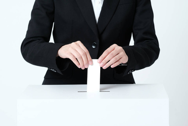 A woman's hand in a suit putting paper in an election ballot box - Photo, Image