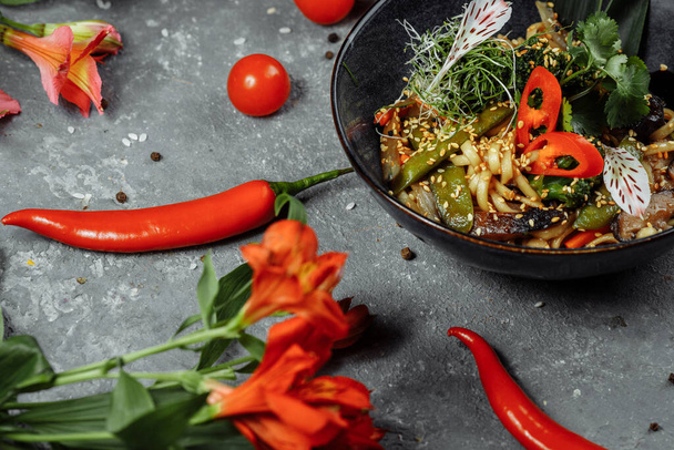 Gebratene Nudeln und Gemüse in einer schwarzen Schüssel umrühren. Leckeres, nahrhaftes asiatisches Essen. - Foto, Bild