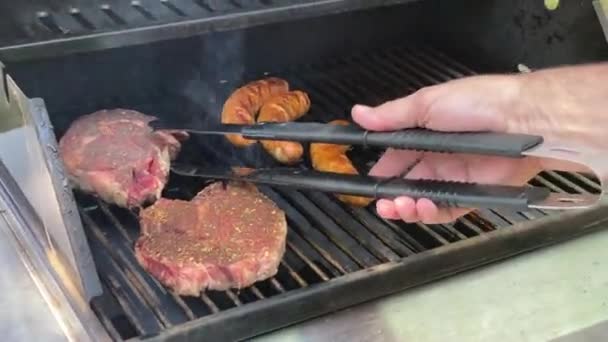 Elämäntapa kesä ulkona mies ruoanlaitto panokset ja makkarat propaani kaasu grilli reikä metalli kielet - Materiaali, video
