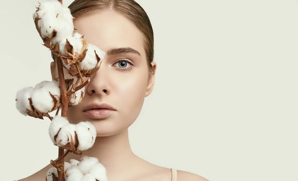 Portrait of beautiful young woman with clean perfect skin posing with cotton flower isolated on white background - Foto, immagini