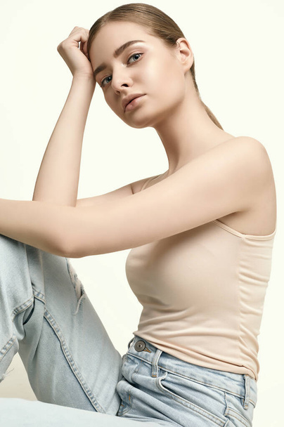 Retrato de una atractiva joven morena en jeans posando sobre un estudio de fondo blanco - Foto, Imagen