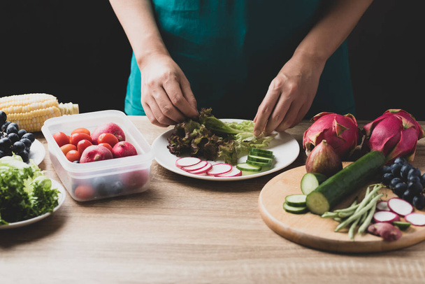Käsi valmistelee tuoreita hedelmiä ja vihanneksia vegaanisalaattiin, terveellistä ruokaa - Valokuva, kuva