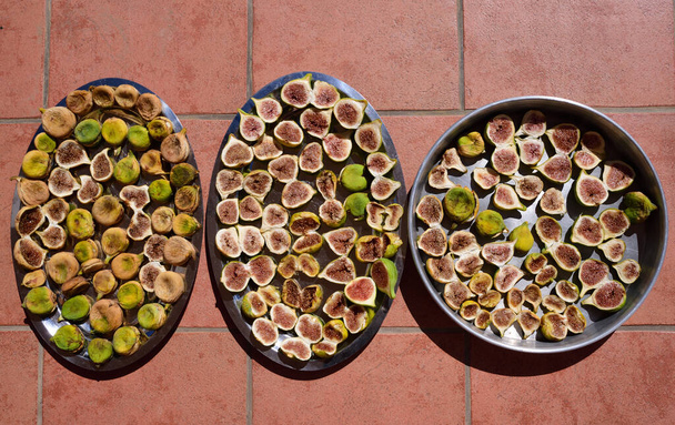Świeże i suszone, zbierane figi leżą obok siebie na różnych tabletkach do wyschnięcia na słońcu we Włoszech - Zdjęcie, obraz