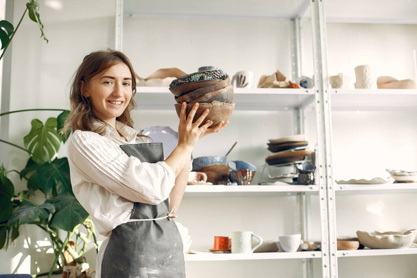 A young woman holds a ceramics dish in her hands - Photo, Image