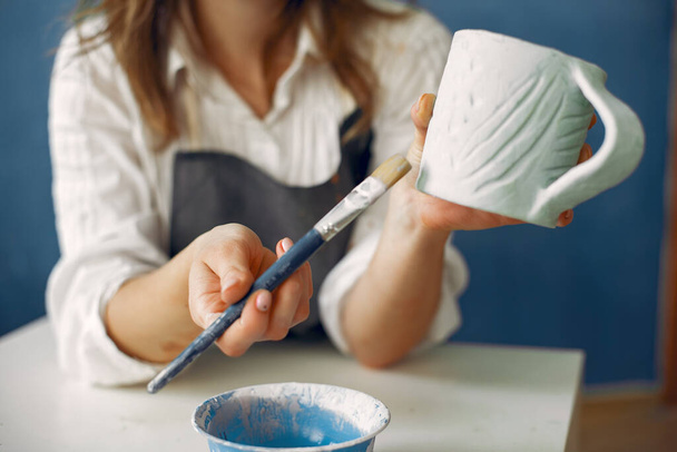 Une jeune femme peignant des plats dans une poterie - Photo, image