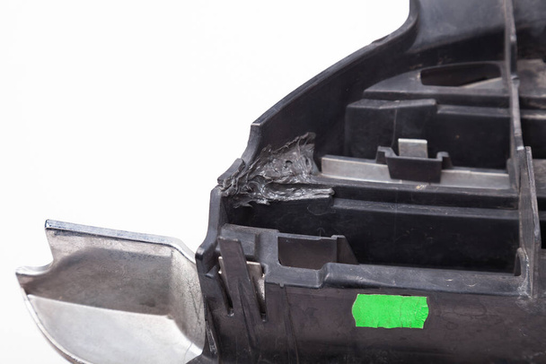 A close-up of a black plastic car part after repair with glue for pre-sale preparation in a workshop during auto-parsing. - Fotó, kép