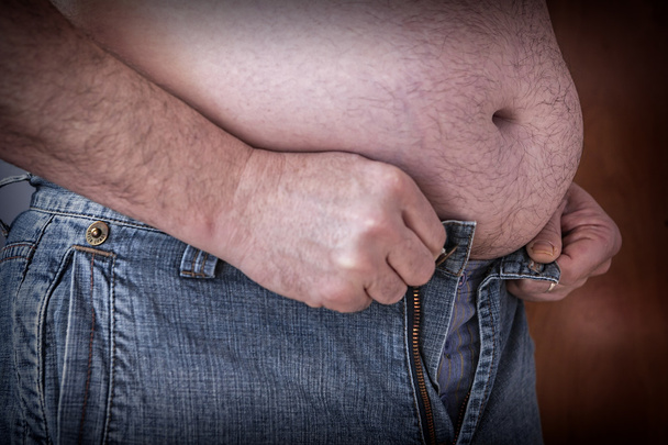 小さすぎる服を締めしようとすると、太りすぎの人 - 写真・画像
