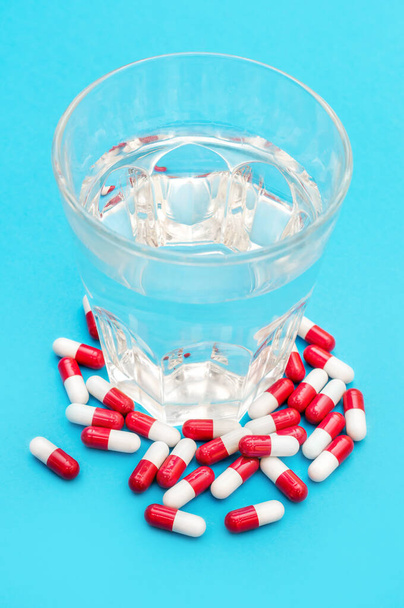 Pills with glass of water on blue. Top view. - Photo, Image