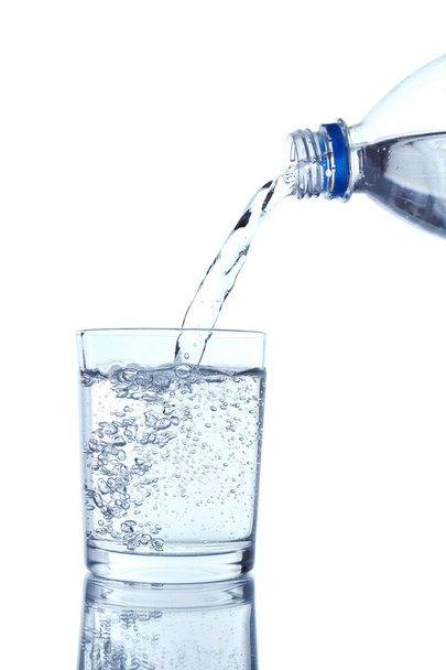 Pour water from bottle into glass, on light blue background - Zdjęcie, obraz