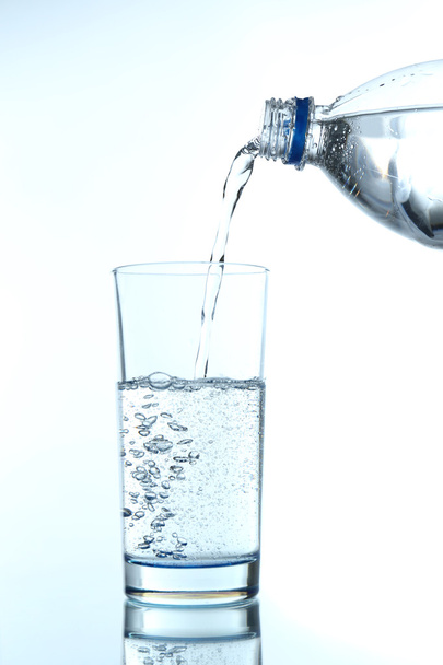 Pour water from bottle into glass, on light blue background - Fotoğraf, Görsel