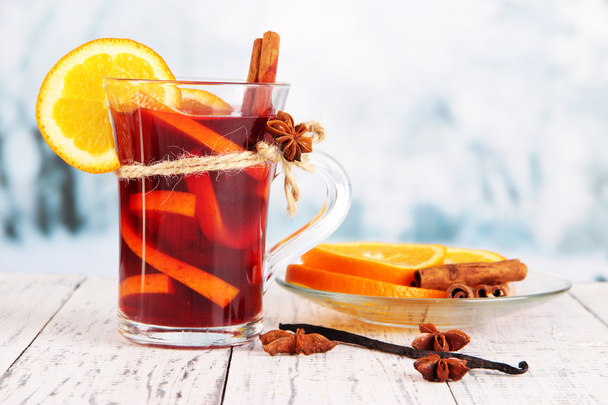 Mulled wine with oranges and spices on table on bright background - Zdjęcie, obraz