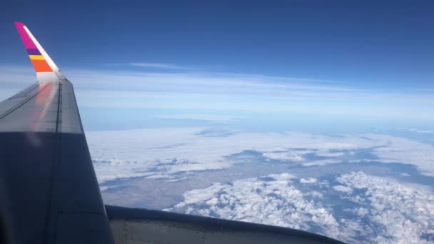 Het raam van het vliegtuig. Mooie witte wolken tegen blauwe lucht. - Video