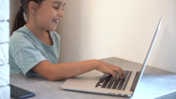 Niño lindo uso portátil para la educación, estudio en línea. Chica tiene tarea en casa escolarización. - Metraje, vídeo