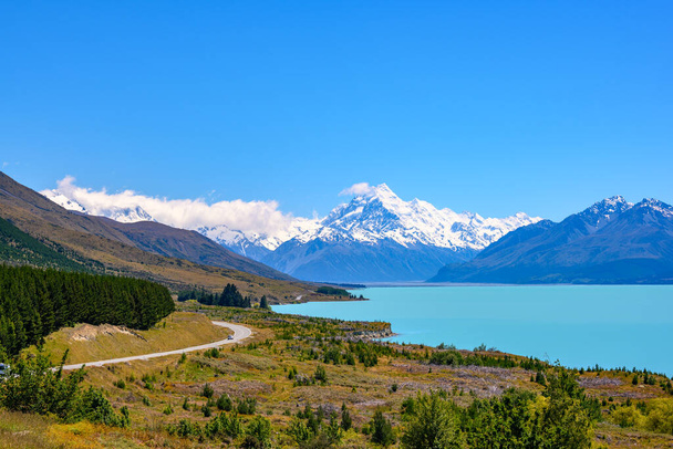 Cesta se klikatí podél jezera Pukaki a Mount Cook za jasného dne na Petrově vyhlídce na Jižním ostrově Nového Zélandu. - Fotografie, Obrázek