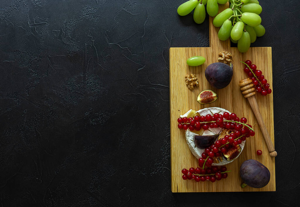 Печь пекла сыр Камамбер с медом, фруктами, орехами и ягодами на мраморном фоне. Вид сверху, вертикальная ориентация, пространство для копирования. - Фото, изображение