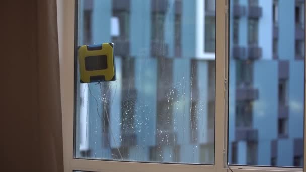 Servizio di pulizia. Piccolo robot bianco rondella di vetro in movimento e rotante su finestre di appartamento, primo piano. Moderni lavavetri intelligenti. 4k filmati - Filmati, video