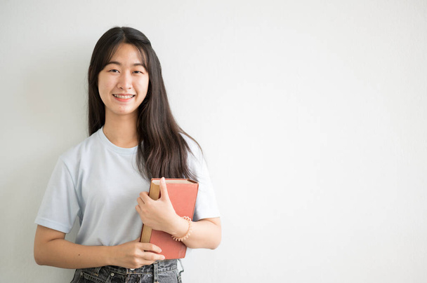 Egy ázsiai főiskolás lány mosolygott az egyetemre, és a kamerába bámult.. - Fotó, kép