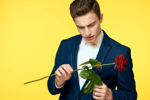 Herrat klassisessa puvussa keltaisella taustalla ja punainen ruusu romanssi rajattu näkymä malli muotokuva. - Valokuva, kuva