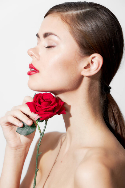 赤い花を持つ女性目を閉じて裸の肩側のビューの魅力  - 写真・画像