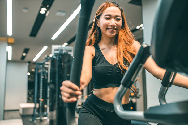 Muscular asian young woman with beautiful  body doing exercises . Sporty girl lifting weights in gym. - Fotografie, Obrázek