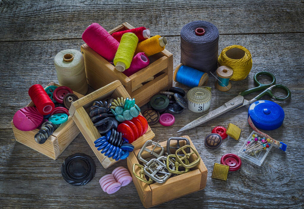 A set for needlework. Old sewing supplies and hand sewing tools. Sewing accessories for sewing, thread, scissors, needles and a tailor counter on an old wooden surface. Retro toning - Foto, Bild