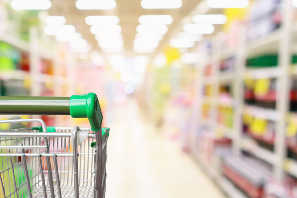 Empty green supermarket shopping cart with abstract blur grocery store aisle defocused background - Foto, Imagen