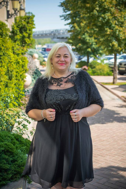 Plus size woman, American or European appearance walks in the city enjoying life. A young lady with excess weight, stylishly dressed in the center of the city. Natural beauty - Foto, imagen