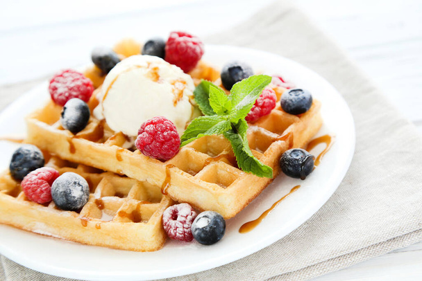Tasty waffles with fresh berries and ice cream on white wooden background - Photo, image