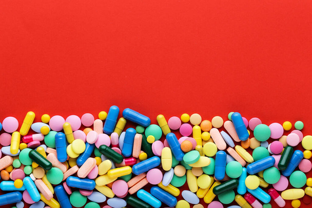 Colorful pills on red background - Foto, Imagen