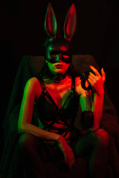 sexy esclava en lencería erótica con máscara de conejito con esposas de cuero - Foto, imagen