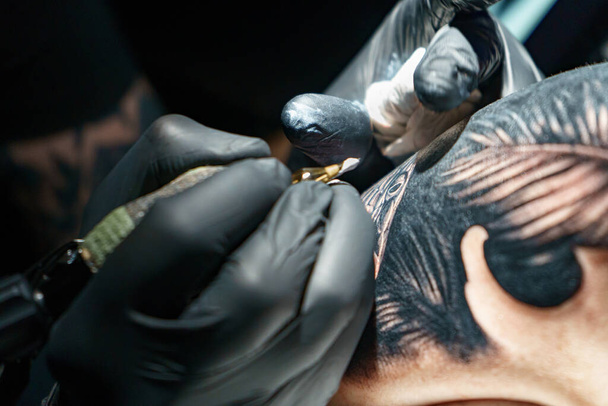 Immagine di maestro che fa tatuaggio nero di serpente per donna - Foto, immagini