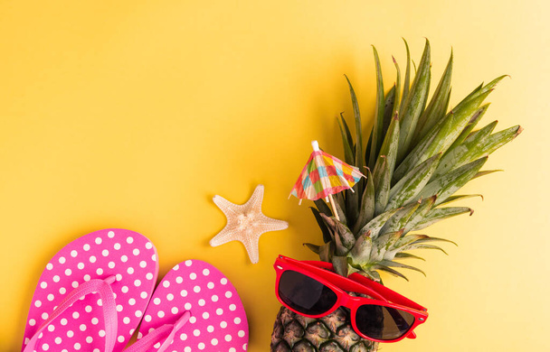 Celebrate Summer Pineapple Day Concept, Top view flat lay of funny fresh pineapple in sunglasses with starfish and slipper, in studio isolated on yellow background, Holiday summertime in tropical - Photo, Image