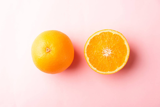 Top view of Fresh half orange fruit slice and full orange in the studio shot isolated on pink background, Healthy food concept - Foto, Imagen