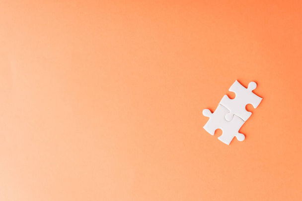 Top view flat lay of two paper plain white jigsaw puzzle game last pieces for solve, studio shot on an orange background, quiz calculation concept - Photo, Image