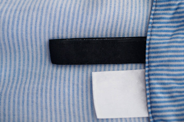 etiqueta de ropa en blanco y negro sobre fondo de textura de tela azul - Foto, imagen