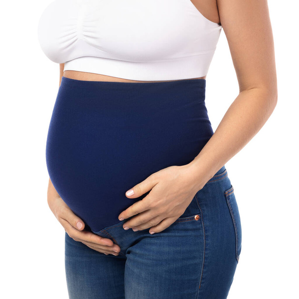 Young pregnant woman wearing maternity jeans isolated on white background - Foto, immagini