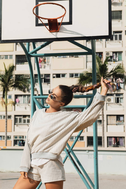 Young stylish woman  is posing on the Choi Hung Estate Basketball Court in Hong Kong city - Фото, изображение