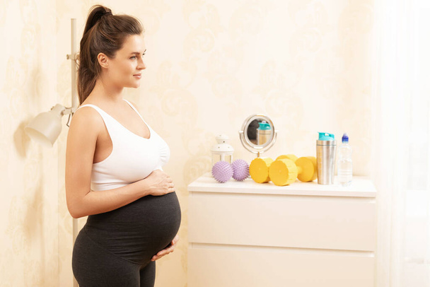 Young pregnant woman during her fitness workout at home - Φωτογραφία, εικόνα
