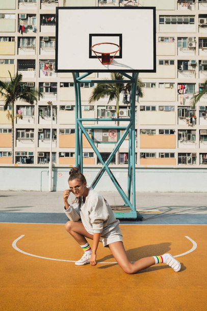 Young stylish woman  is posing on the Choi Hung Estate Basketball Court in Hong Kong city - Фото, зображення
