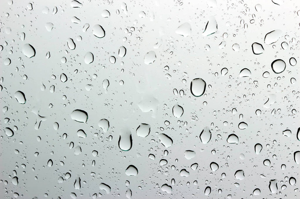 Una pequeña gota de lluvia descansa sobre el vidrio después de la lluvia. - Foto, Imagen