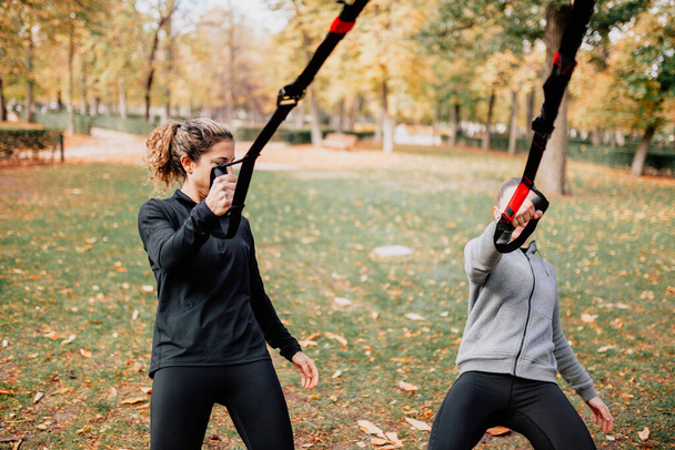 Naiset treenaavat trxin kanssa ulkona puistossa. - Valokuva, kuva