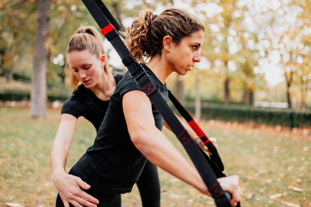 Naiset treenaavat trxin kanssa ulkona puistossa. - Valokuva, kuva