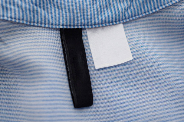 leeres schwarz-weißes Bekleidungsetikett auf blauem Texturhintergrund - Foto, Bild