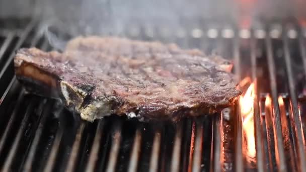 Közel a finom marhahús steak lángoló grill. - Felvétel, videó