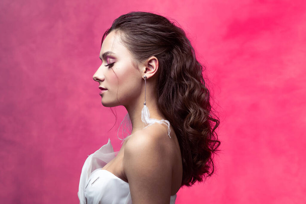 Portrait of a young beautiful woman in elegant white, textured pink background. - Φωτογραφία, εικόνα
