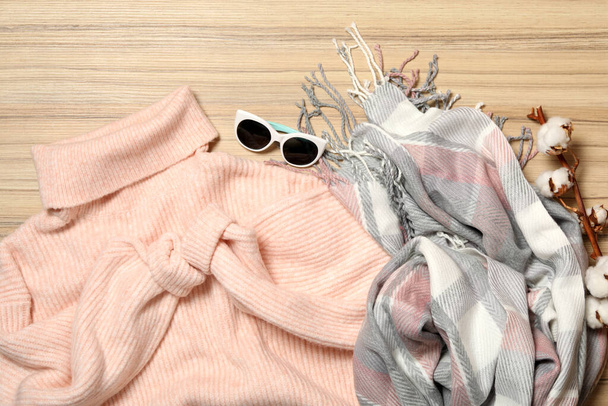 Flat lay composition with warm sweater on wooden background. Autumn season - Zdjęcie, obraz