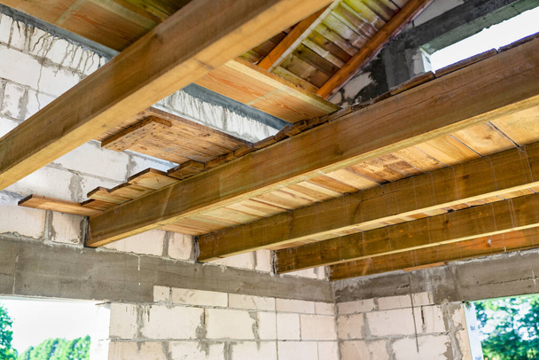 solives en bois préparées pour la pose du plancher du grenier d'une maison en brique blanche nouvellement construite. - Photo, image